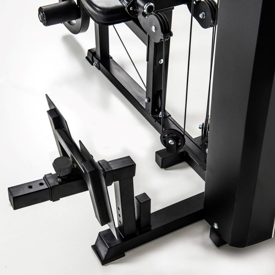 Iš arti nufotografuotos jėgos staklės TOORX MSX-90, rodančios jų apatinę dalį su kojų pratimų priedu